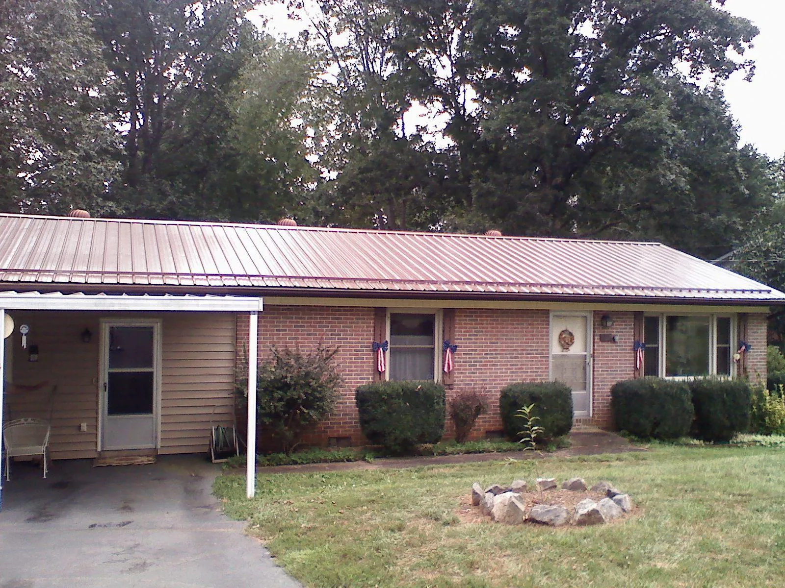 Bronze metal roof and carport on a brick ranch home — Roof Repair work by our crew in Hartland